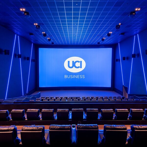 Bild eines leeren Kinosaals mit Blick auf die Leinwand, auf der "UCI Business" steht